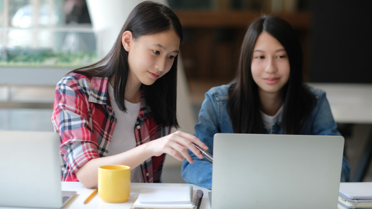 Deux étudiants révisent ensemble pour préparer l'EJU, avec un ordinateur portable et des notes
