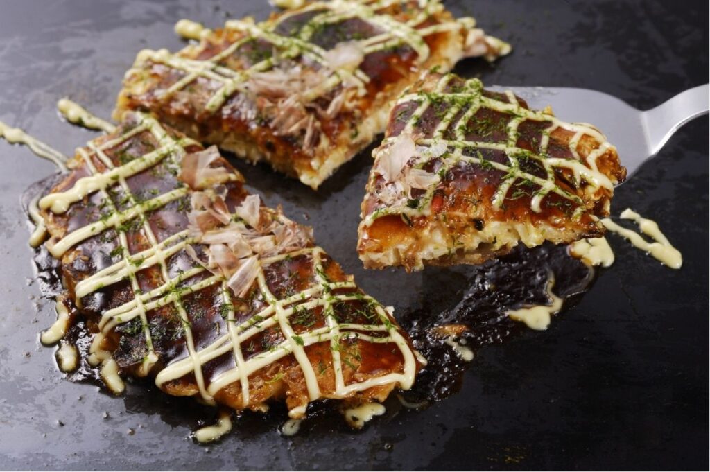 Okonomiyaki, crêpe salée japonaise garnie de sauce et de mayonnaise