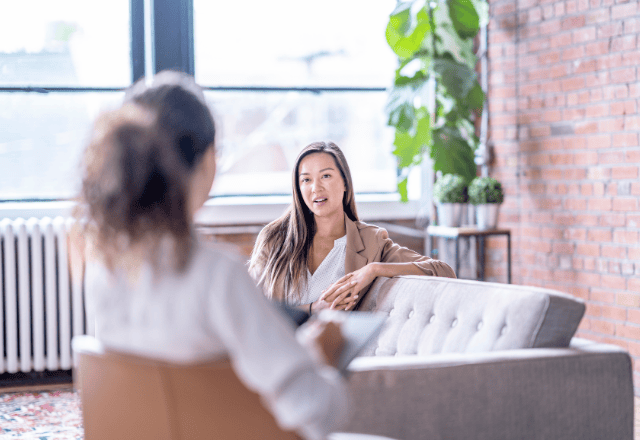 Counseling session between a therapist and a client in a bright, comfortable office setting.
