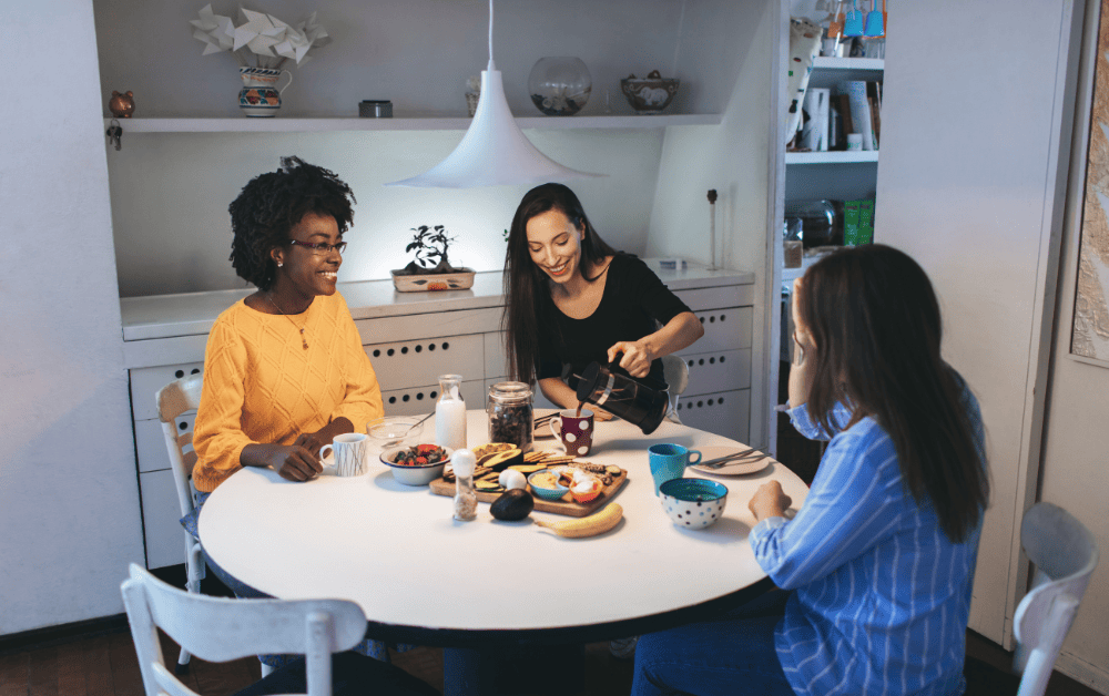 Three women enjoying a meal together in a share house kitchen, highlighting the community and social aspect of this accommodation option in Japan.
