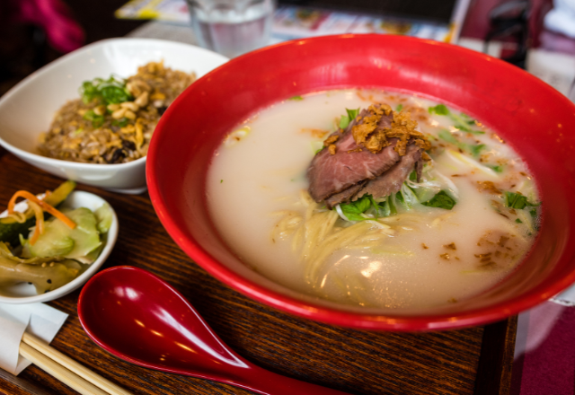 Bowl of ramen with creamy broth, sliced meat, and side dishes, served at a restaurant in Kobe.