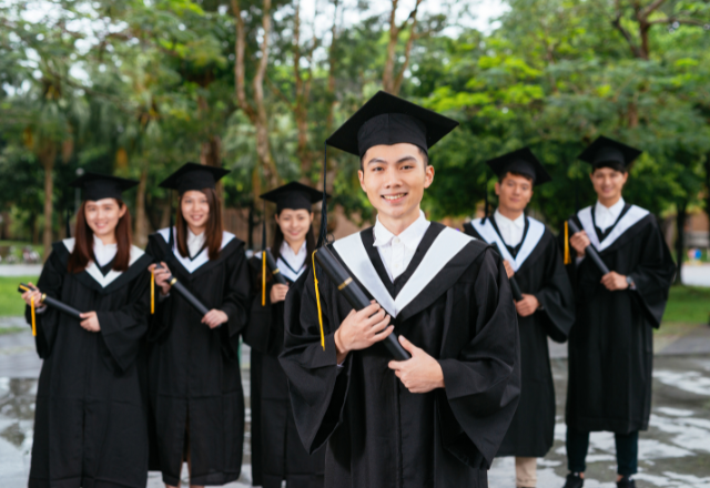 Group of international students in graduation gowns celebrating university completion in Japan.