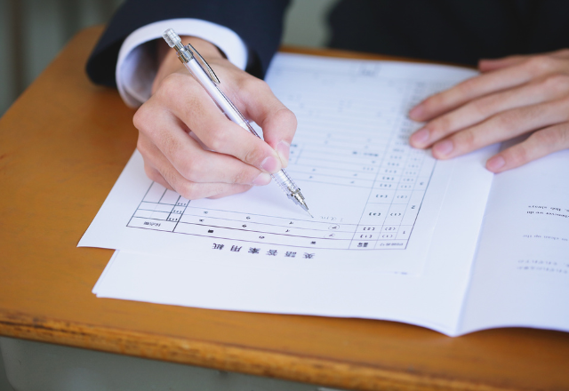 Close-up of a student filling out a Japanese university application form with a pen