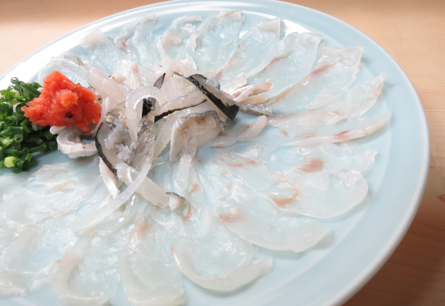 Thinly sliced fugu (pufferfish) sashimi beautifully arranged on a plate.