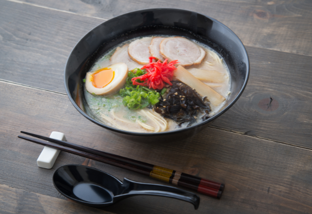 Bowl of Hakata ramen with rich tonkotsu broth, pork slices, boiled egg, and toppings.