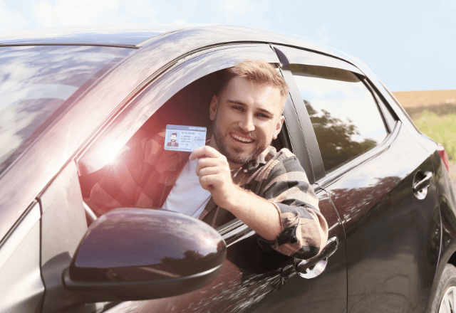 Foreign driver showing his new Japanese driver's license while sitting in a car.