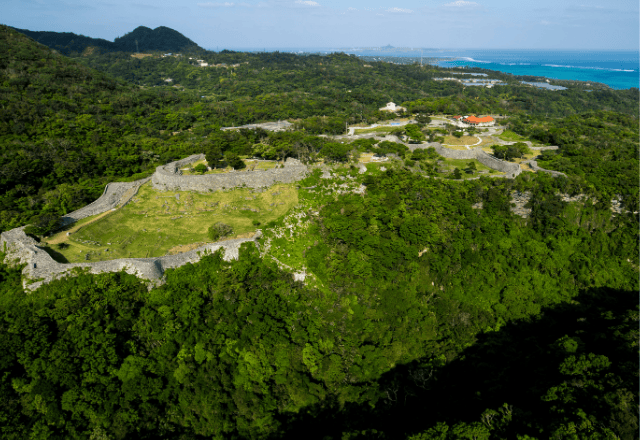 Aerial view of Nakijin Castle Ruins surrounded by dense forest and overlooking the coastline in Okinawa