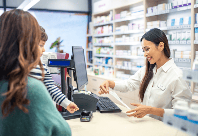 A friendly pharmacist assisting a customer at a Japanese pharmacy counter.