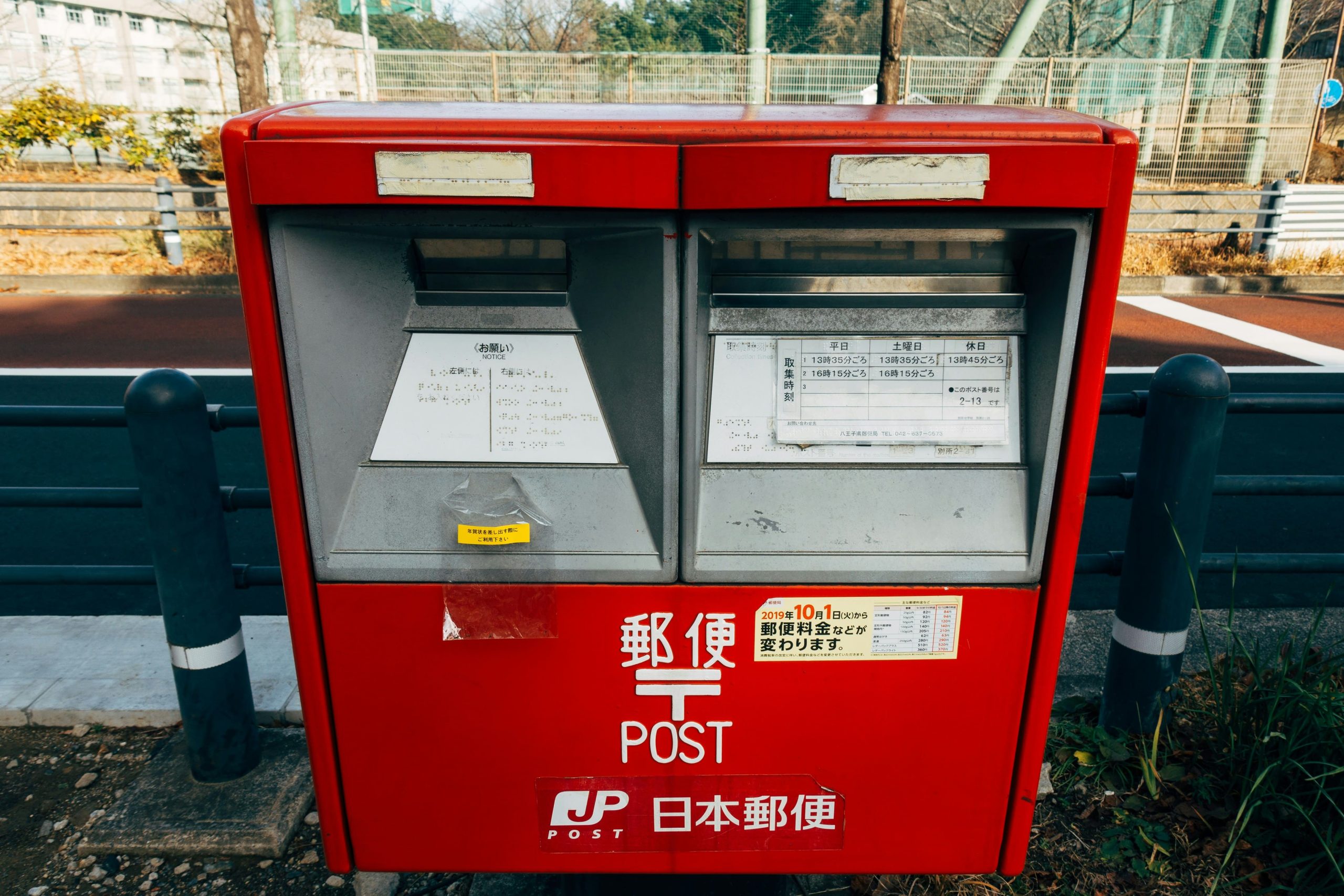 A bright red Japanese postbox with separate slots for domestic and international mail, including a schedule for collection times.